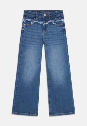 Weite Jeans in mittelblauem Denim, mit einem ausgefransten Bund, orangefarbenen Nähten und Taschen auf beiden Seiten.