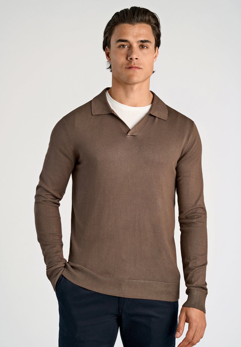 Ruskea pitkähihainen poolopaita, jossa on V-pääntie ja teksturoitu neule. Kuvioitu litteä kaulus ja resorit hihansuissa, yhdistetty tummiin housuihin.