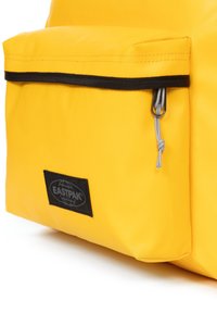 Bolsa Eastpak amarilla con un bolsillo frontal con cremallera negra, tirador gris y parche de logo negro. Material suave y duradero.