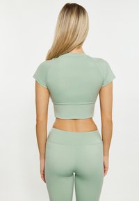 Mentolově zelený sportovní crop top s krátkým rukávem, měkká látka, přiléhavý design a bezešvý lem. Spárován s odpovídajícími legínami.