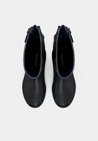 Fekete gumibakancs, sima felülettel, arany díszítésekkel az oldalán, és sötétkék belső béléssel. Kerek orrú és alacsony sarkú.