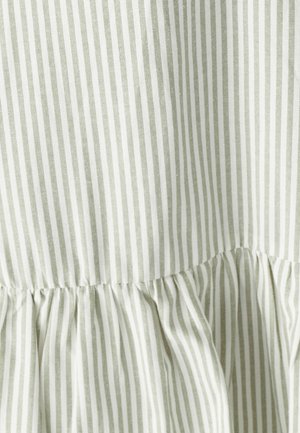 Pasičasta tkanina v svetlo zeleni in beli barvi, z mehke gube na robu. Tekstura izgleda gladka in lahka.