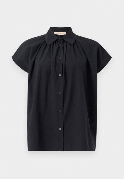 Melnā īsām piedurknēm blūze ar pogu priekšpusi, klasisku apkakli un saplacinātu detaļu pie kakla. Mīksta, gluda auduma tekstūra.