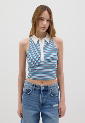 Gestreifter, ärmelloser Croptop in Blau, Weiß und Lila mit einem weißen Kragen und Knopfleiste. Kombiniert mit hoch taillierten, lässigen Denim-Jeans.