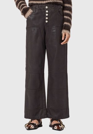 Sorte vidbenede bukser med høj talje og store forlommer med knaplukning, båret med en stribet, fluffy sweater og sko med spænde i ko-print.