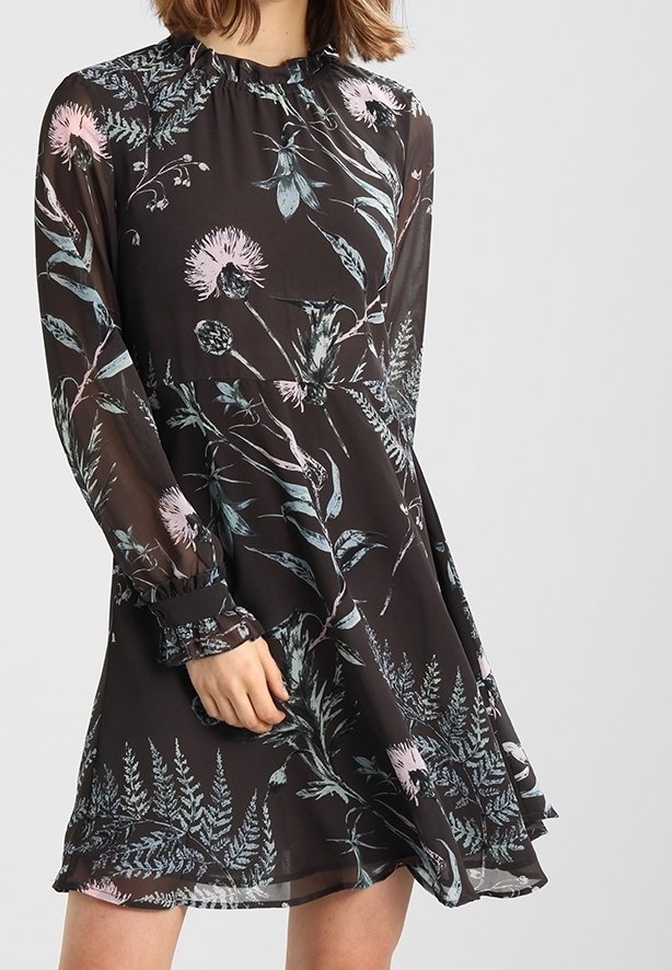 Schwarzes Kleid mit Blumenmuster in Pastellrosa und Blau. Hergestellt aus leichtem Stoff, mit langen Ärmeln und einem gerüschten Ausschnitt.