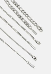 Chaînes en argent de différentes épaisseurs et designs, y compris des maillons et un fin mesh, avec des fermoirs et des étiquettes de marque estampillées "Calvin Klein."