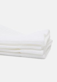Calcetines blancos de punto apilados, con un diseño acanalado y una textura suave. Sin patrones ni acentos presentes. Longitud clásica hasta el tobillo.