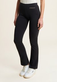 Pantaloni jersey neri con design a campana, caratterizzati da un sottile logo Freddy in finitura metallica sulla cintura. Texture liscia in tutto il tessuto.