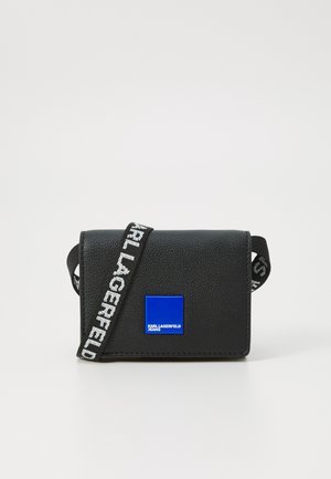 Black textured faux leather bag with blue logo plaque, adjustable strap featuring white text, compact rectangular shape.
