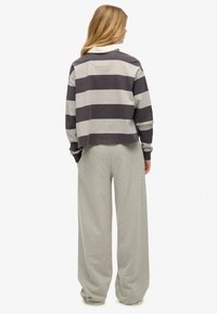 Korte, langslijf top in grijs en donkergrijs gestreept, gecombineerd met hooggepolsterde, wijde grijze sweatpants die een relaxed fit laten zien.