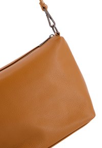 Tan leren tas met een gladde textuur en een gestructureerde vorm. Beschikt over een metalen rits en een afneembare riem met een metalen clip.