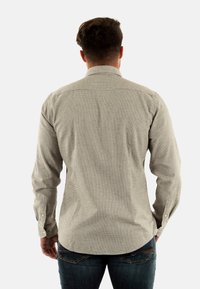 Lichtgrijze, gestructureerde langwerpige blouse met een puntkraag, knopenmanchetten en een ronde zoom, gecombineerd met donkerblauwe jeans.