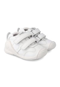 Weiße Lederschuhe mit zwei Klettverschlüssen, gerundeten Zehen und Gummisohlen. Merkmale sind graue Akzente und eine strukturierte Verzierung an der Ferse.