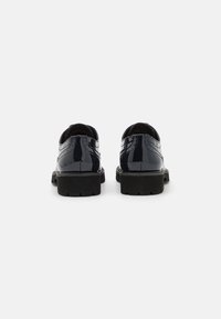 Scarpe in pelle verniciata nera con finitura liscia, punte arrotondate e suole in gomma nera texturizzata, caratterizzate da cuciture dettagliate sulla parte superiore.