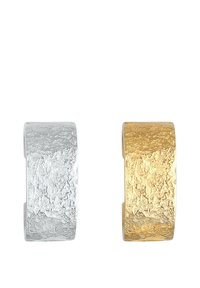 Strukturerede øreringe i sølv og guld i metal; sølvet har en glat overflade, mens guld har en rå, hamret struktur.