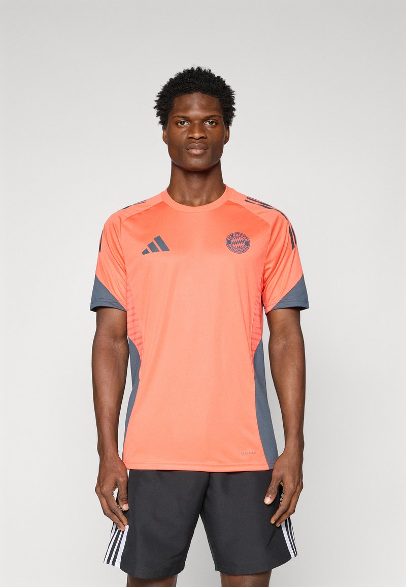Oranje sportshirt met grijze accenten, met korte mouwen, ronde halslijn en een Bayern München-logo op de borst.