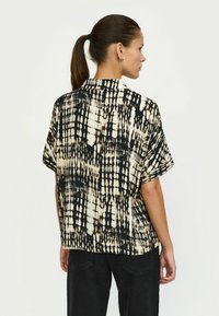 Cămașă cu mânecă scurtă în negru și bej, cu un model tie-dye, având guler și o croială lejeră. Textură fină și material ușor.