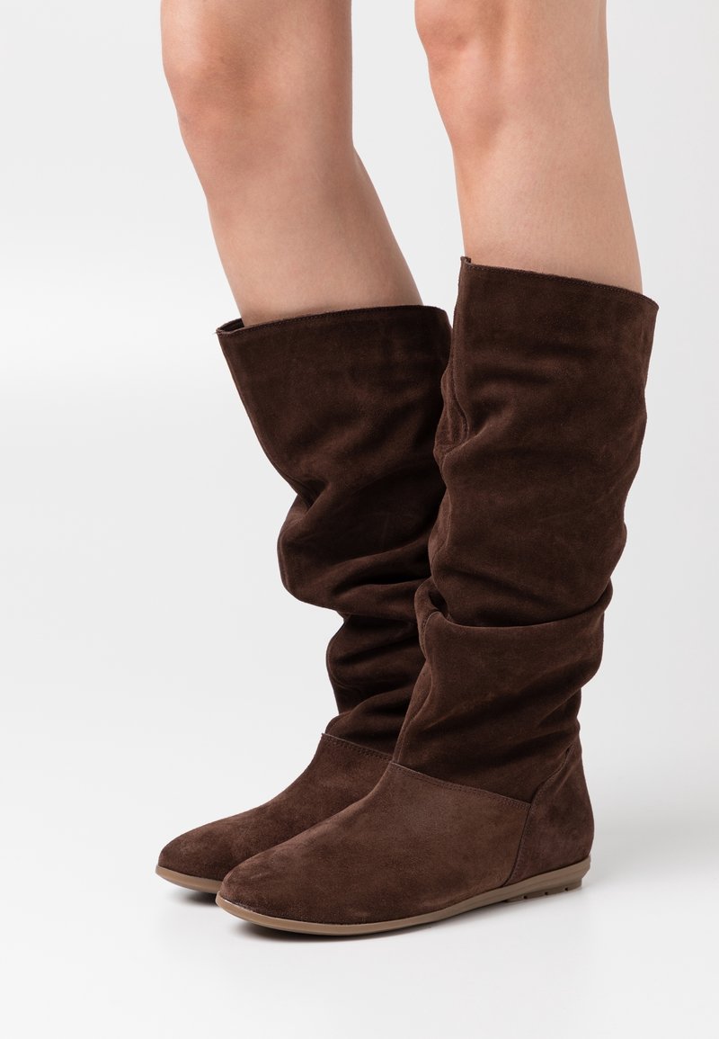 Bottes montantes en daim marron à design décontracté, avec une texture douce et des semelles plates pour un confort et une facilité de port.