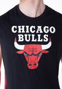 Musta toppi, jossa on valkoisella painettu "CHICAGO BULLS" -teksti ja suuri punainen härkälogo, jossa on valkoiset sarvet ja mustat yksityiskohdat.