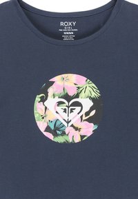 Camiseta de algodón orgánico en azul marino con un gráfico floral circular y un logotipo de corazón blanco en el centro. Diseño de cuello redondo.
