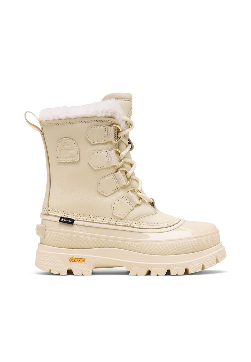 Botte d'hiver beige avec une finition vernie brillante, doublure en fausse fourrure et semelle Vibram ; dotée d'œillets métalliques et d'un design à lacets.