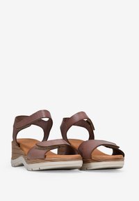 Sandalias de cuña de cuero marrón con diseño de punta abierta, correas ajustables y entresuela texturizada. Presenta una plantilla acolchada y un ajuste seguro.