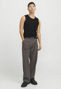 Sort ribbet tanktop parret med grå plisserede bukser. Det komplette look omfatter et sort bælte og sorte sko. Enkle og moderne designs.