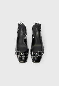 Melnas ādas slingback kurpes ar kvadrātu purngalu, studētu siksnu un sprādzes detaļām. Zema papēža un gluda tekstūra, parādītas no augšas.