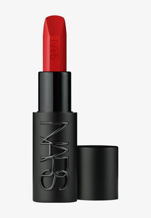 Rossetto rosso NARS con custodia nera, parzialmente estratto, accanto al suo tappo rimosso su sfondo bianco.