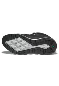 Zapatilla deportiva negra con un upper texturizado, que presenta una suela de goma con un patrón de tracción distintivo en gris y un acento verde.