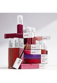 Maybelline Super Stay Matte Ink flytande läppstift i olika nyanser, som har rektangulära förpackningar med vita lock och djärva färgdekaler.