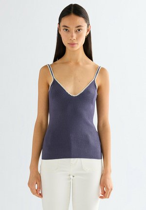 Granatowy prążkowany top na ramiączkach z białym obramowaniem wzdłuż dekoltu w kształcie litery V i ramiączek, dopasowany krój, miękka faktura oraz bez rękawów. Lekki materiał.