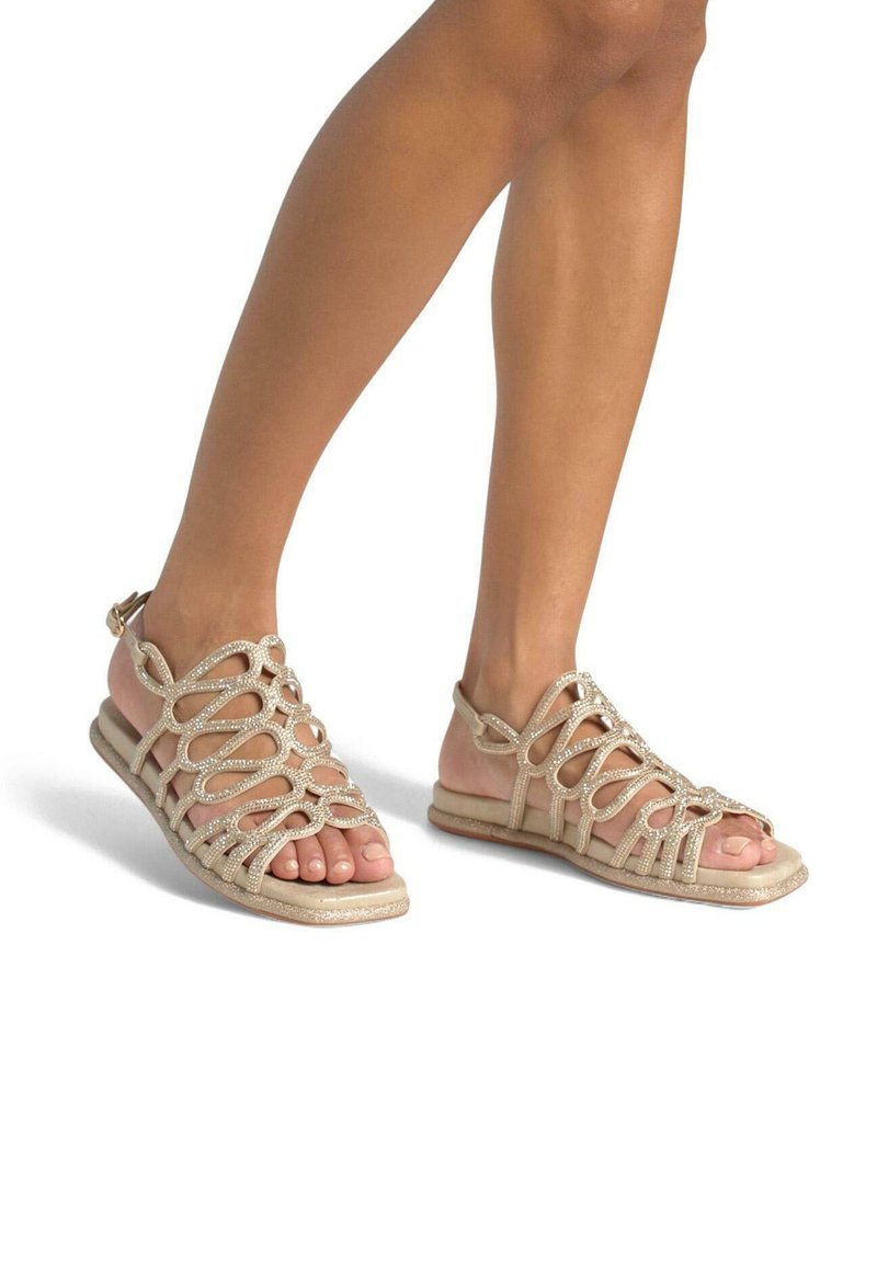 Beige sandalen met banden, voorzien van decoratieve lussen, glinsterende accenten, een open teen ontwerp en een zachte platte zool.