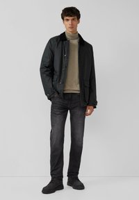 Czarna wodoodporna kurtka z kołnierzem, zestawiona z jasnoszarym golfem, ciemnymi dżinsami i czarnymi butami. Gładka faktura, dopasowany krój.