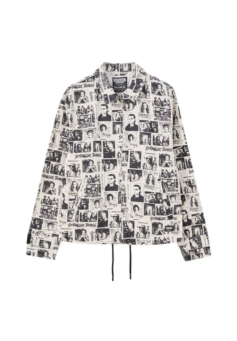 Chaqueta de color negro y blanco con cuello que presenta diversas imágenes impresas y texto de "Stranger Things", con un dobladillo ajustable y mangas largas.