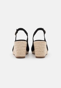 Čierne semišové wedge sandále s opleteným juty podpätkom, dizajnom na členok a nastaviteľným remienkom. Čistá, minimalistická estetika.