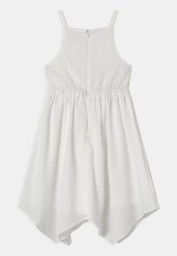 Vit klänning med justerbara axelband, elastisk midja och asymmetrisk fåll. Tillverkad av ett mjukt tyg med dragkedjestängning i ryggen.