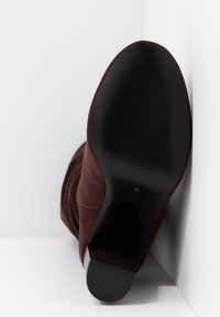 Bruna mocka ankelstövlar med en slät svart gummisula, med en något spetsig tå och subtila sömnadsdetaljer längs sidan.