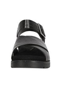 Svart lädersandal med en texturerad yta, som har ett brett band, justerbar spänne och en dämpad innersula. Platt gummisula.