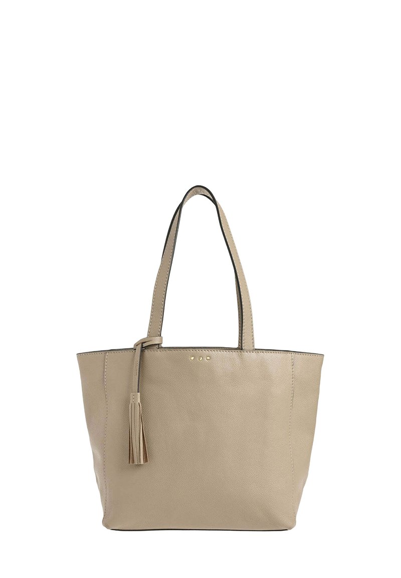 Sac fourre-tout en cuir beige avec deux poignées de transport, détail en forme de pompon et trois clous décoratifs à l'avant. Design simple et structuré.