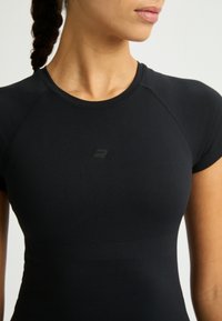 Camiseta atlética negra de manga corta, con un diseño ajustado y elegante que presenta un sutil detalle de textura en la parte delantera y un acento con el logo.