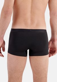 Schwarze Boxershorts mit glatter Textur und elastischem Bund, von hinten betrachtet. Der Stoff ist leicht und formschlüssig.