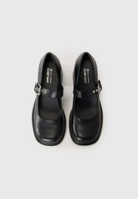 Pair of black vegan leather Mary Jane shoes with square toes and buckled straps, shown from above on a white background.