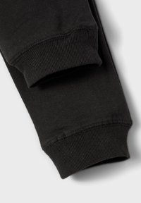 Schwarze Baumwoll-Jogginghosen mit gerippten Bündchen, die eine glatte Textur und eine enge Passform um die Knöchel bieten. Einfaches Design, ohne Muster oder Akzente.