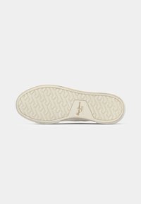 Semelle d'une sneaker beigne avec un motif de semelle géométrique et un logo de marque embossé au centre sur un fond blanc.