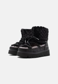 Fekete bokacsizmák plüss anyagból, steppelt felső résszel, fényvisszaverő részletekkel és vastag fekete talppal. Átfedő csipkés kivitel és logós részlet jellemzi.