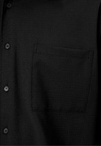 Chemise noire à boutons avec un tissu texturé. Elle dispose d'une poche sur la poitrine gauche et de boutons noirs le long de la patte de boutonnage.