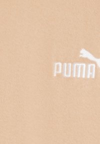 Peach-colored fleece fabric featuring a textured surface and a white embroidered logo with a leaping cat and the word "PUMA."