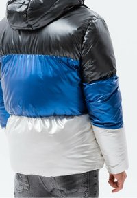Steppjacke mit einem Farbblock-Design in Schwarz, Blau und Weiß, glänzendem Finish und Kapuze. Strukturierter Stoff mit elastischem Saum.